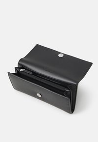 Portefeuille en cuir noir avec une finition texturée, comportant une fermeture à bouton pression, une poche zippée intérieure et des compartiments spacieux pour les cartes et les billets.