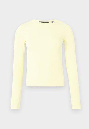 Majica dugih rukava rebraste teksture u nježnoj žutoj boji, s okruglim izrezom i pristajućim krojem, izrađena od rastezljivog materijala za udobnost.