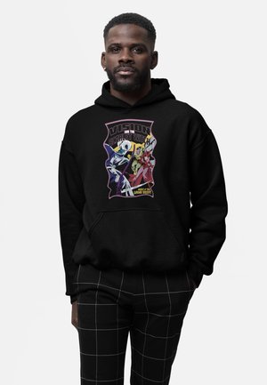 Hombre con sudadera negra con capucha con gráfico de Vision y Scarlet Witch en estilo cómic, combinado con pantalones negros con patrón de cuadrícula blanca.