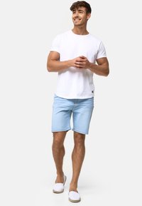 Hvit bomull t-skjorte kombinert med lyseblå denim-shorts og hvite slip-on sko. Løs passform, enkelt design og ingen synlige mønstre eller logoer.