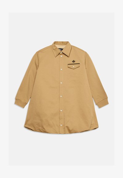 Chemise à manches longues couleur fauve avec col pointu et une seule poche poitrine ornée d'un petit emblème de feuille d'érable.