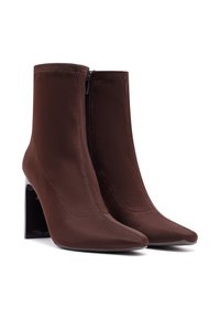 Bottines en tissu marron à bout pointu et fermeture éclair sur le côté, avec un talon bloc noir brillant. Texture lisse, détails de couture minimalistes.