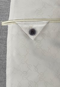 Men's blazer with a textured black fabric on the left and a smooth cream lining featuring a subtle pattern, detailed with a dark button.