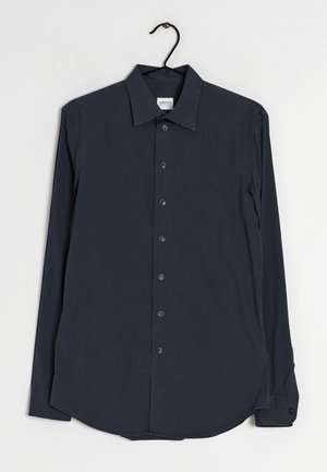 Chemise noire à manches longues boutonnée avec col sur un cintre noir sur fond blanc uni.