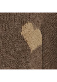 Detalje af striktrøje i brunt med en beige hjerteformet lapp. Teksturen er blød og fnugget og viser en blanding af materialer.