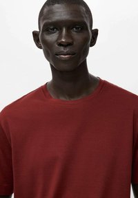 Czerwona koszulka z krótkim rękawem, okrągły dekolt, gładka faktura, minimalistyczny design, dopasowana do ciała, gładka bez wzorów i ozdób.