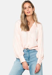 Pink plaid blouse with a lightweight fabric, button-down front, and balloon sleeves. Paired with high-waisted blue denim jeans.