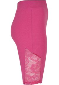 Leggings de algodón rosa con un panel de encaje en el muslo exterior. El diseño cuenta con una cintura ajustada y una textura suave en toda la tela.