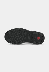 Suela de zapato de goma negra con un patrón texturizado de zigzag, que presenta una banda central y un pequeño detalle circular rojo con la palabra "HUNTER" grabada.