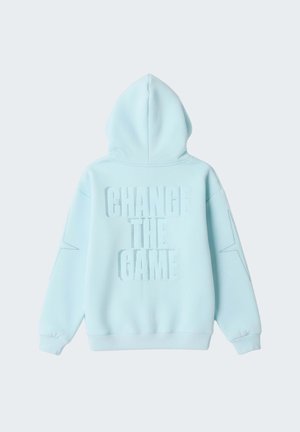 Sudadera con capucha azul claro con texto "CAMBIA EL JUEGO" en la espalda y diseños de estrellas en las mangas.