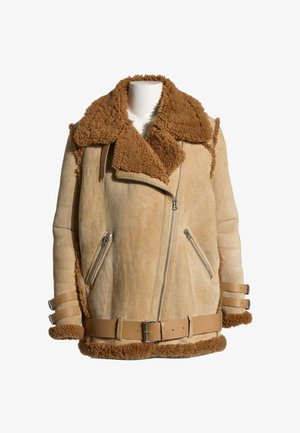 Veste en shearling beige avec grand col, fermeture éclair diagonale sur le devant, poches zippées et sangles en cuir à boucles aux poignets et à la taille.