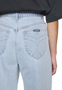 Jeans de denim azul claro com bolsos traseiros que apresentam um design em ziguezague e uma pequena etiqueta "ROLLA'S". Com alta cintura e um corte relaxado.