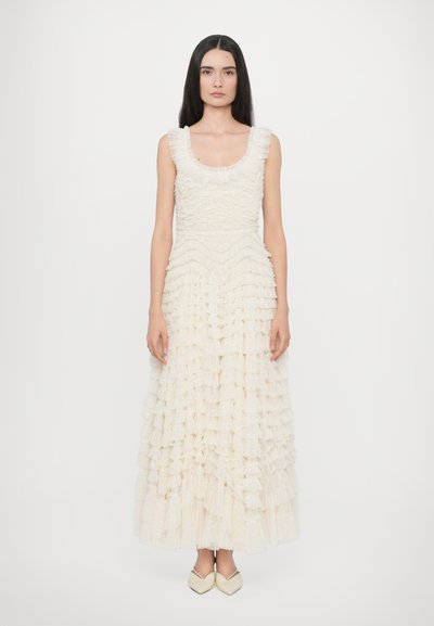 Ruffled, sleeveless dress in cream with a fitted bodice and layered skirt. Features a scalloped neckline and a floor-length hem.