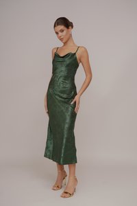 Satin πράσινο φόρεμα με λαιμόκοψη και σιλουέτα εφαρμοστή, μήκους μέχρι το γόνατο, με περίπλοκη floral υφή. Συνδυασμένο με χρυσά ψηλοτάκουνα με λουράκια.