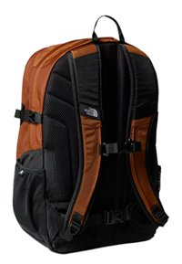 Czarny i brązowy plecak z wyściełanymi bokami, siatkowym materiałem, regulowanymi paskami oraz przednią kieszenią; zawiera klamry oraz logo z boku.