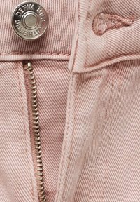 Ljust rosa denim tyg har en dragkedjeslutning med silverdetaljer och en knappaccent, vilket visar en fin, texturerad väv.