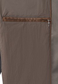 Braune Jacke mit einer zerknitterten Textur, ausgestattet mit einer Reißverschlusstasche und kontrastierenden Abschlüssen. Glattes Material auf einer Seite, strukturiert auf der anderen.