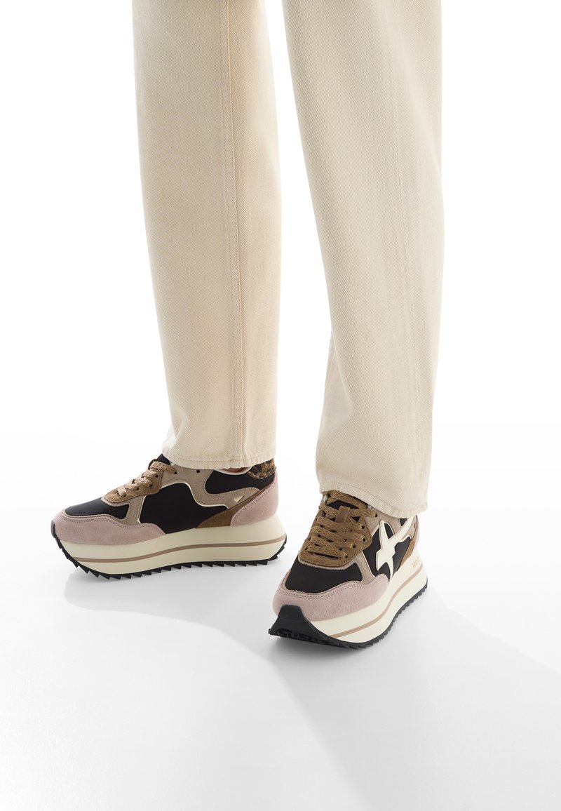 Sportliche Sneakers mit einer Mischung aus schwarzen, beigen und braunen Wildleder-Obermaterialien, strukturierten Sohlen und einer dicken weißen Plattform. Schnür-Design.