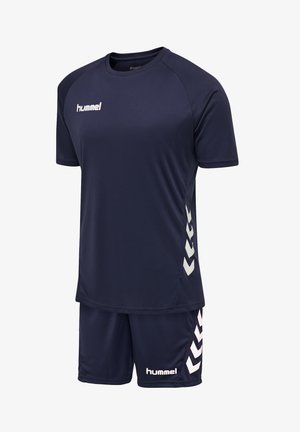 Completo sportivo blu scuro con maniche corte e pantaloncini, caratterizzato da loghi bianchi "hummel" e strisce a chevron sui lati.