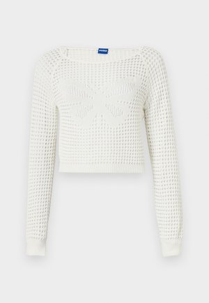 Bela skrajšana pletena jopica z teksturiranim vzorcem, ki ima v sredini dizajn metulja in rebraste manšete na rokavih.