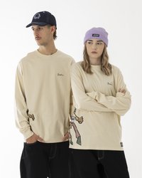 Bež majice dugih rukava s zelenim detaljima, s grafikom crtanog junaka sa strane. Jedan model nosi tamnu kapu, dok drugi nosi ljubičastu beanie.