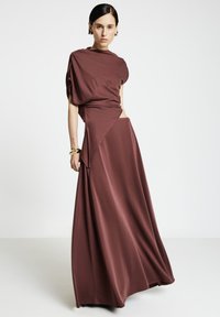 Langes weinrotes Kleid aus weichem Stoff mit asymmetrischem Design, drapierten Ärmeln und einem seitlichen Ausschnitt für eine moderne Silhouette.