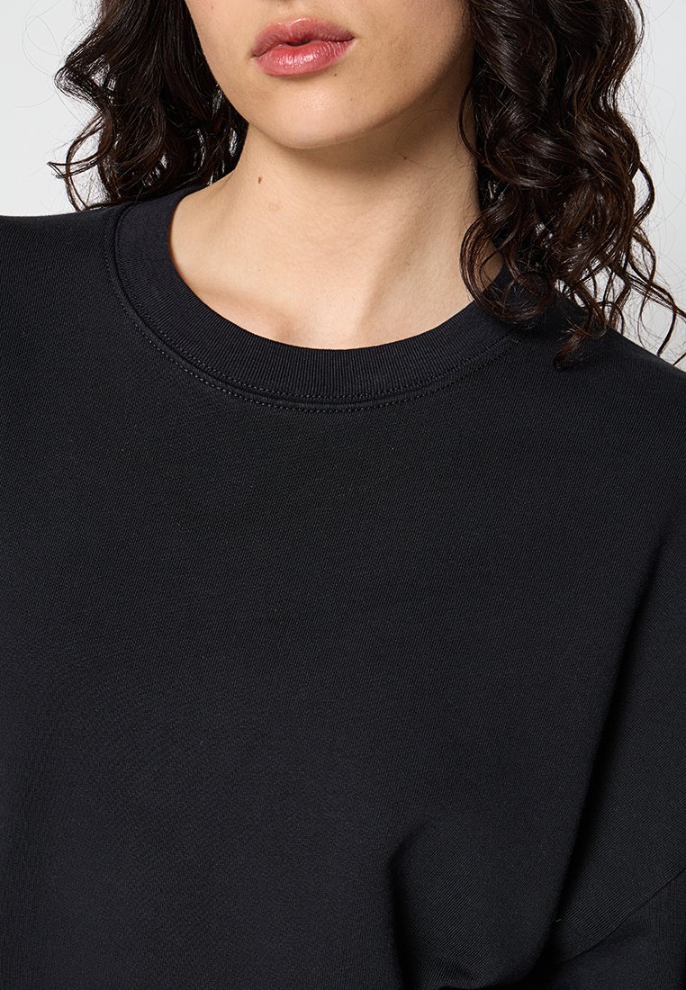 Schwarzer Sweatshirt mit rundem Ausschnitt und strukturiertem Stoff. Mit Bündchen und Saum, die eine subtile Nahtdetail aufweisen.