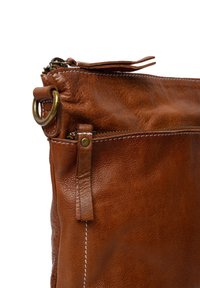 Borsa in pelle marrone con chiusura a zip, accessori in ottone e dettagli di cucitura a vista. Design compatto con una tasca laterale.