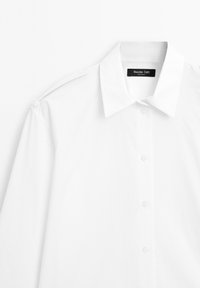 Camicia bianca con bottoni in cotone misto. Caratterizzata da un colletto classico, maniche lunghe e una superficie liscia. Include un'etichetta sul colletto.