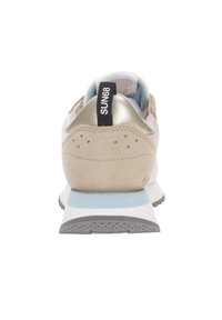 Zapatilla deportiva de ante beige con un talón metálico dorado, detalles en azul y una suela de goma texturizada. Presenta una etiqueta de logo negra en el talón.