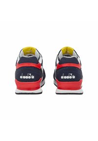 Scarpe da ginnastica blu e rosse con accenti bianchi, dotate di una tomaia in rete, collare imbottito e logo sul tallone, montate su una suola bianca.