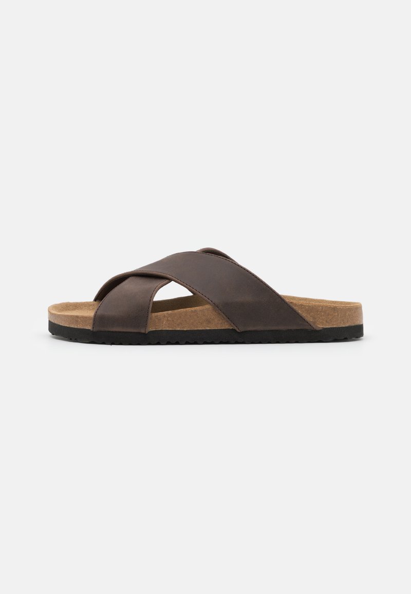 Sandal tipo slide em pele castanha com uma palmilha de cortiça, design de tiras cruzadas e uma sola de borracha preta texturizada para aderência e estabilidade.
