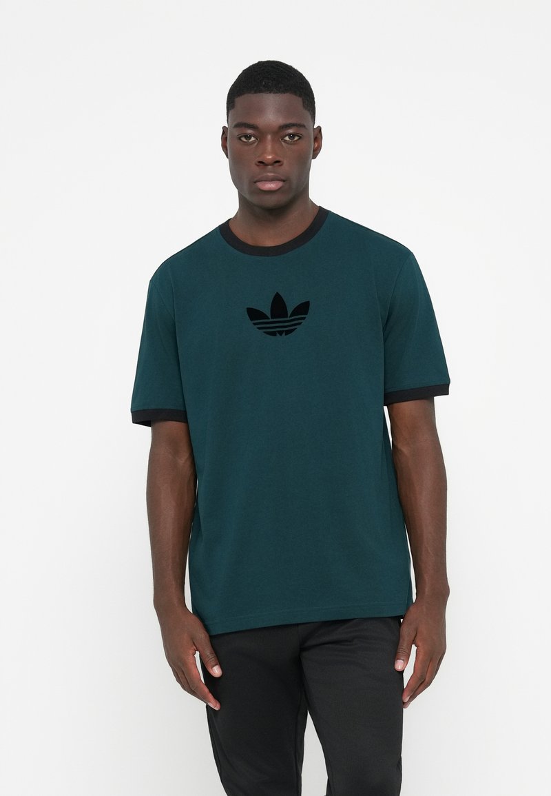 Dark teal t-shirt made of cotton, featuring short sleeves with black accents and a black Adidas logo on the chest. Smooth texture.