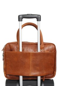 Borsa da viaggio in pelle marrone con due manici, attaccata a una valigia nera con ruote, dotata di una cerniera e di una tasca frontale piatta.