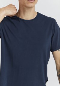 Námornícky modré bavlnené tričko s kruhovým výstrihom, krátkymi rukávmi a voľným strihom. Obsahuje jemné švy a rozparok na boku.