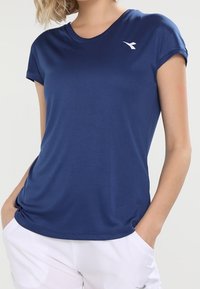 Navy blue athletic t-shirt made of breathable fabric, featuring short sleeves and a white logo on the chest, with a relaxed fit.