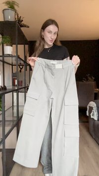 Pantaloni cargo grigi chiari con molteplici tasche laterali, design a gamba dritta e tessuto strutturato. Presenta una vita di altezza media.