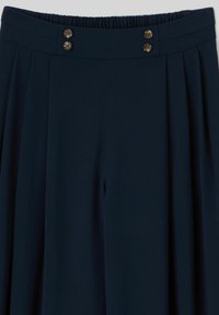 Jupe bleu marine plissée, avec taille élastique et quatre boutons marron disposés par paires à l'avant.