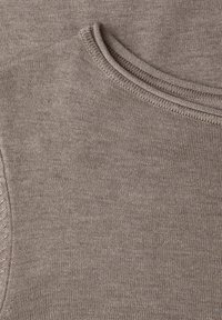 Tissu de pull en tricot beige, présentant une texture lisse et un col arrondi. Contient des détails de couture subtils le long des bords.