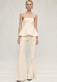 Off-white strapless peplum-top parat med utsvängda byxor, som har en slät textur och vida benöppningar. En enkel och modern design.