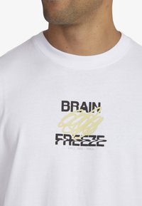 White cotton t-shirt featuring black and yellow graphic text. Round neck, relaxed fit, with a modern design.