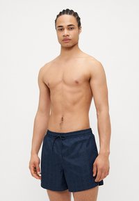 Mørkeblå badeshorts med mønstret design, elastisk talje og snøre lukning. Letvægtsstof, over knæet længde.