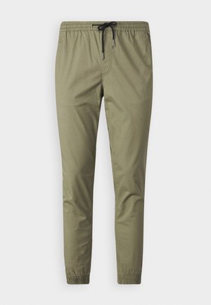 Pantaloni jogger di un verde oliva chiaro realizzati in tessuto morbido, dotati di una vita elasticizzata con cordino e polsini elasticizzati alle caviglie.