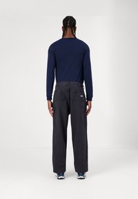 Long-sleeve navy shirt paired with high-waisted, dark gray cargo pants featuring side pockets and a branded tag on the back.
