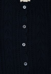 Marineblauer Strickcardigan mit strukturiertem Muster, gewellten Kanten und sechs runden, hellen Knöpfen.