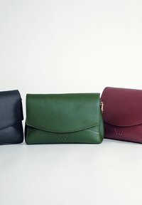 Tři kožené kabelky: černá s hladkým povrchem, tmavě zelená s mírným leskem a vínová s diskrétním logem na přední straně.