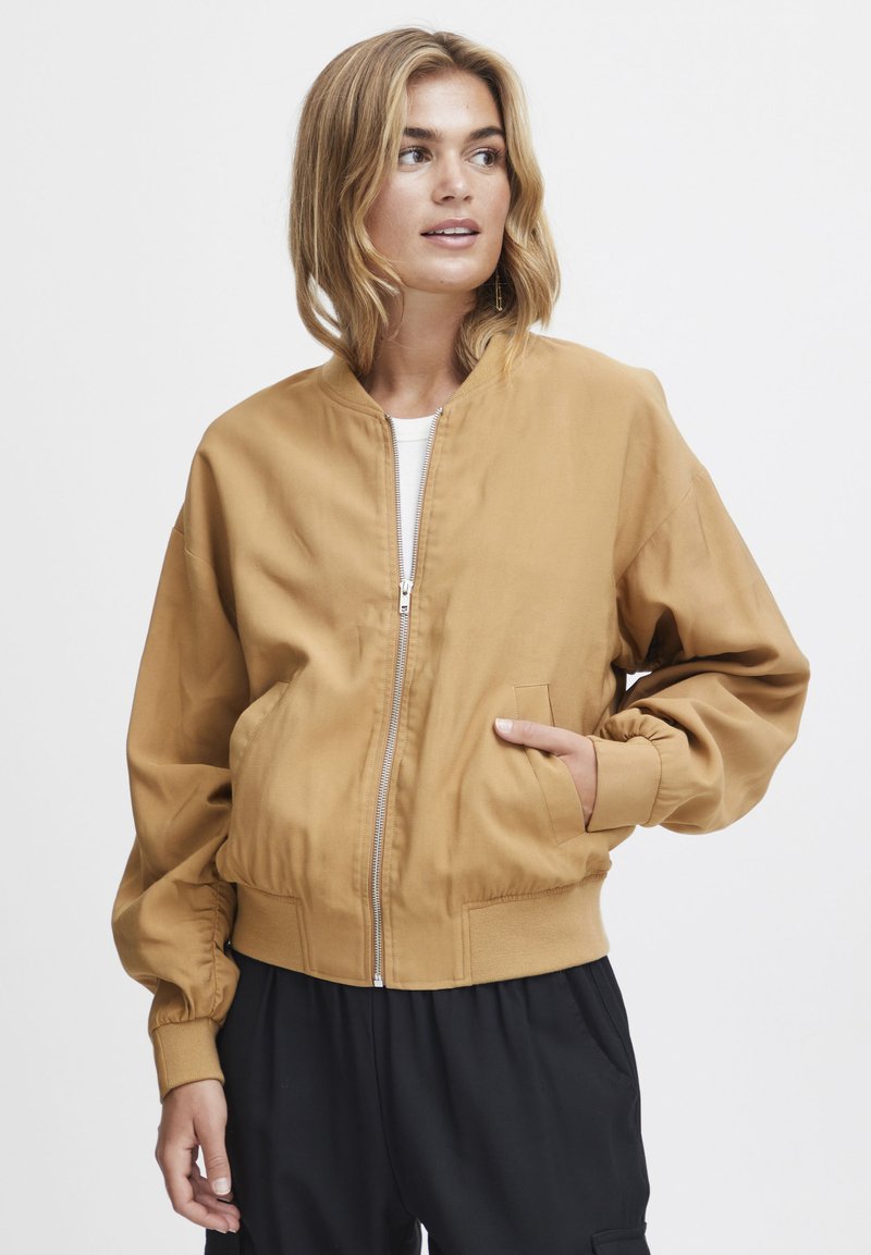 Hnedá bomber bunda vyrobená z hladkej tkaniny. Má predný zips, rebrované manžety a dve bočné vrecká. Jednoduchý dizajn bez viditeľných vzorov.