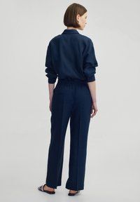Chemise bleu marine à coupe décontractée avec un col et des poignets à bouton, associée à un pantalon large assorti avec une taille élastique.