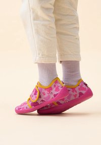 Pink fabric shoes with yellow trim, featuring a patterned design of various shapes. Soft texture with a rubber sole for grip and comfort.