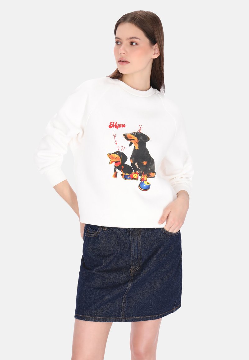 Weißes Sweatshirt mit einer Grafik von zwei Dackeln und dem Schriftzug "Mymo." Kombiniert mit einem dunklen Jeansrock.